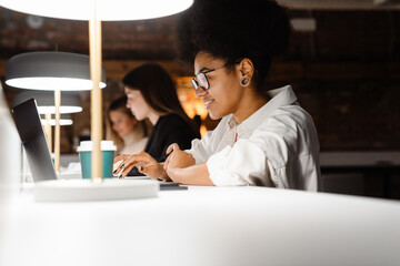 African woman smiling while working on laptop in office