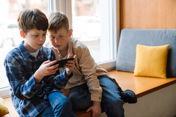 Two boys using mobile phone while sitting in classroom
