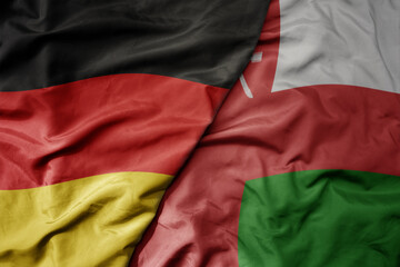 big waving realistic national colorful flag of germany and national flag of oman .