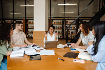 Group of students having discussion while studying together in library