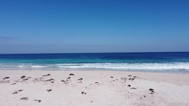 Picturesque blue, clear water with white waves.  White sand and seaweed