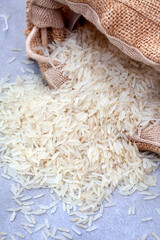 Basmati rice pouring from a burlap sack on grey