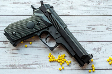 airsoft handgun with yellow bb, on white wooden background
