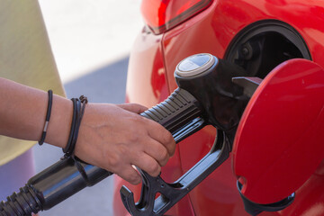 close up of a hand pumping gas into a car