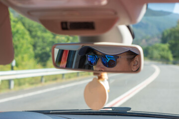 Driver's sunglasses reflected in the rearview mirror of a car