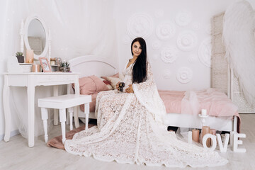 Pregnant woman strokes hugging the belly tummy abdomen enjoying pregnancy hold child shoes. Future family, baby infant expecting child inside, lady in white dress 

