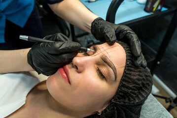 Fototapeta na wymiar master performs the procedure of permanent eyebrow makeup for the client