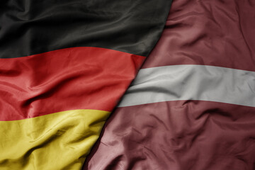 big waving realistic national colorful flag of germany and national flag of latvia .