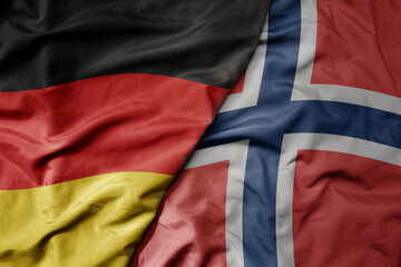 big waving realistic national colorful flag of germany and national flag of norway .