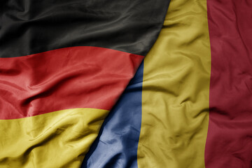 big waving realistic national colorful flag of germany and national flag of romania .
