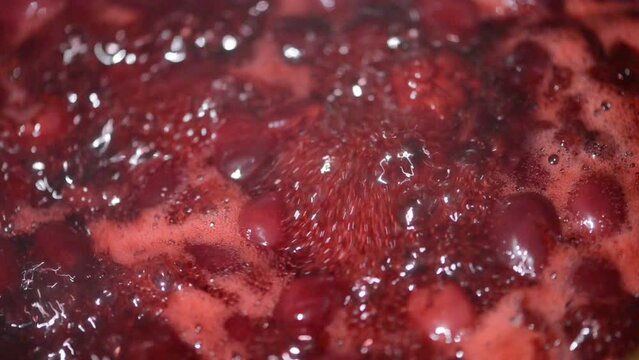 Mixing with a spoon, cooked cherry fruit jam in a pot. Mixing the cherries. 