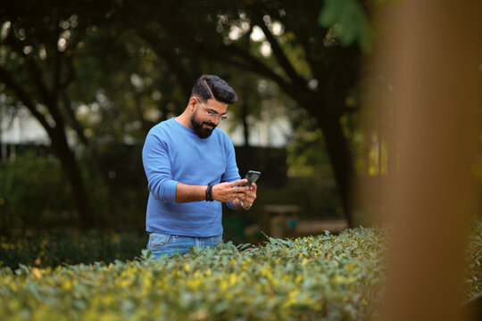 Young Indian man using smartphone at park.