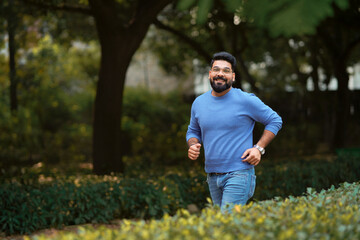 Young indian man running or jogging at park.