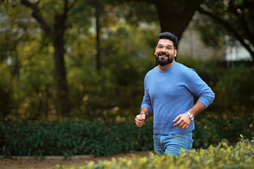 Young indian man running or jogging at park.