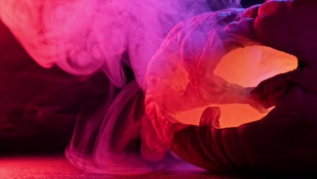 Halloween pumpkin shining from inside with smoke around. Smoke with changing colors. Smoke appearing from pumpkin. Aged carved pumpkin with wrinkles. Old halloween pumpkin. Close-up in 4K, UHD
