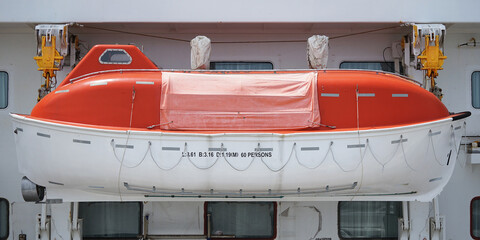 Orange lifeboat on the belly deck of a large ship
