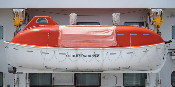 Orange lifeboat on the belly deck of a large ship