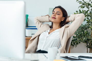 Beautiful elegant business woman stretching while working on computer in the office