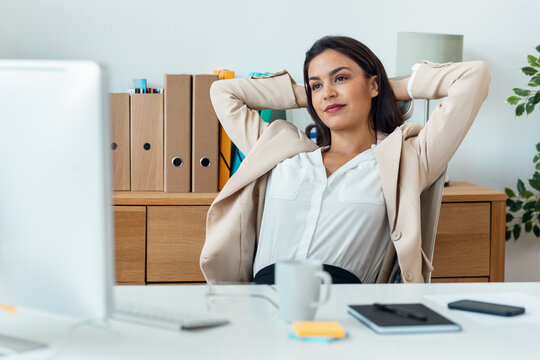Beautiful elegant business woman stretching while working on computer in the office