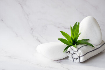 White stone product display platform. SPA background concept. White stones, towel, and leaves of green plant on marble background with copy space. Body care and beauty treatment concept. Copy space.