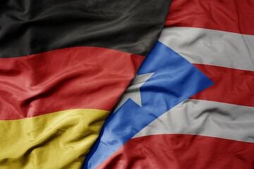 big waving realistic national colorful flag of germany and national flag of puerto rico .
