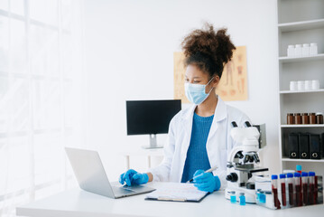 .Young scientists conducting research investigations in a medical laboratory, a researcher in the foreground is using a microscope in laboratory for medicine.