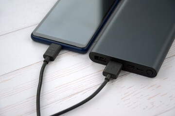 Power bank for charging mobile devices. Black smart phone charger with power bank.
