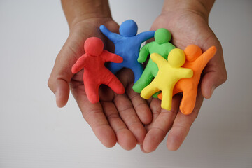 Close up hands holds colorful plasticine people. Human figures from plasticine sculpture.  Concept,...