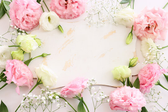Top view image pink flowers composition and empty board over white background