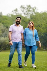 Fototapeta premium young indian couple holding hand each other and walking in park