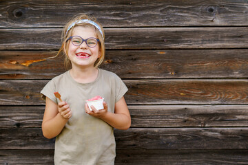 Little adorable preschool girl with eyeglasses eating berry and watermelon ice cream sundae in cup...