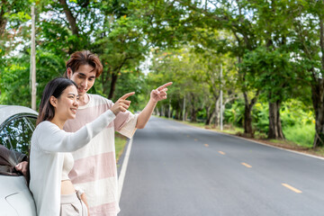 Obraz premium Young asian couple get out of the car and walk to enjoying the view, standing near the car, Man and woman looking at sunset and beautiful nature, Boy and girl standing by the machine