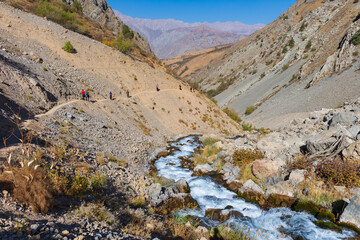 Fototapeta na wymiar Beautiful autumn mountain landscape. Mountainous region of Uzbekistan. Tourist trail. A pure mountain river flows in a mountain valley.