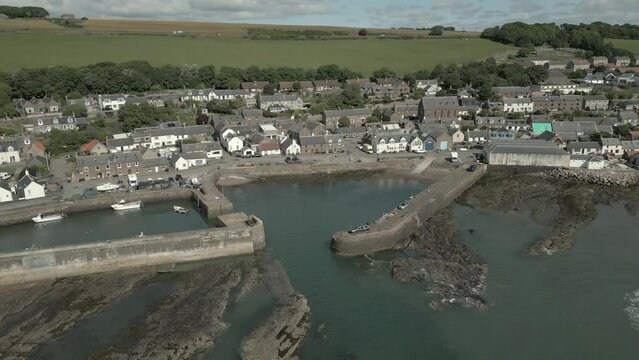 An aerial view of Johnshaven harbour and town on a sunny day, taken from the sea, Aberdeenshire, Scotland, UK. Tracking and panning drone shot left to right