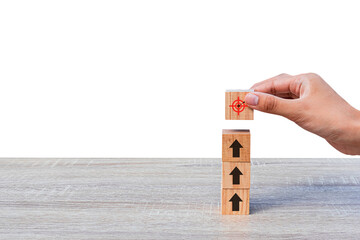 Hand placing wooden blocks as steps towards target and arrow up on wooden table. Business success...