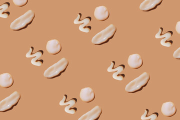 White сosmetic smears of creamy texture on a pastel background. Many happy face made of sunscreen. SPF sunblock cream. Pattern, natural skin care concept
