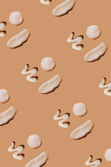 White сosmetic smears of creamy texture on a pastel background. Many happy face made of sunscreen. Cream mockup. SPF sunblock cream. Pattern, natural skin care concept