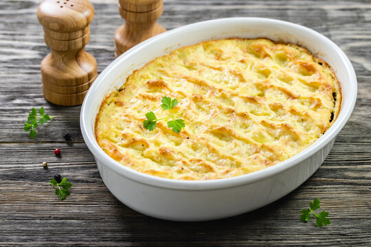 Potato gratin in baking dish on wooden background. Top view, copy space, flat lay.
