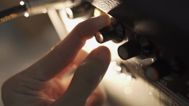 Adjusting tone and volume knobs on a guitar amplifier