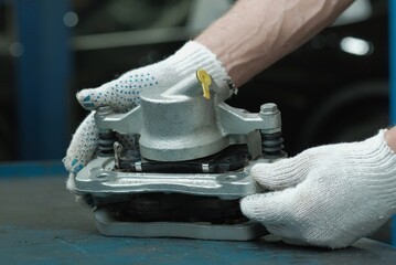 Car repair in a car service. The brake caliper is in the hands of an auto mechanic. The braking...