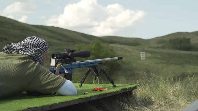 An athlete shoots a rifle with an optical sight from a prone position