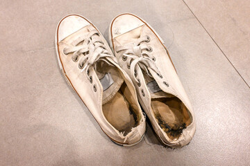 Naklejka premium Old and dirty white cream canvas sneakers.