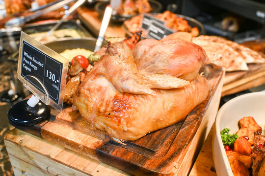Herbs marinated and oven roasted capon turkey on wooden board in food court.