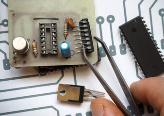 Hand holding an integrated circuit. 14 pins IC and its socket on electronic card.