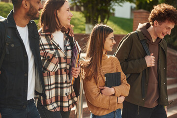 Four young students in casual clothes are together outdoors