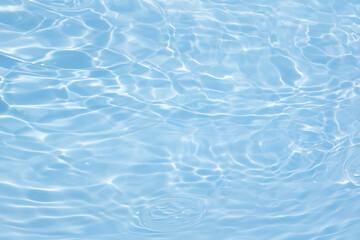 Blue water with ripples on the surface. Defocus blurred transparent blue colored clear calm water surface texture with splashes and bubbles. Water waves with shining pattern texture background.