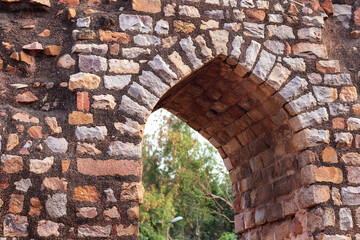 Ancient red sandstone minaret old architecture and old arch gate. Part of the Qutb complex (Qutub), an array of monuments and buildings at Mehrauli in Delhi, India. UNESCO World Heritage Site