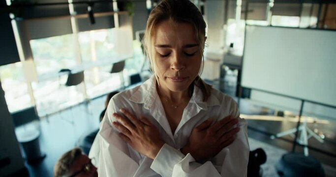A young blonde girl in a white shirt is worried before making a blind fall into the hands of her colleagues in the office. mutual trust therapy