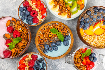 Bowl of granola with yogurt and fresh berries on a texture table. Yogurt berries, acai bowl, spirulina bowl. Healthy food, balanced breakfast. Strawberries, blueberries, kiwi, peach, almonds and chia.