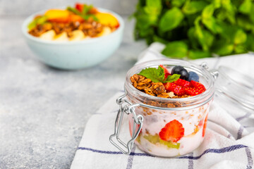 Bowl of granola with yogurt and fresh berries on a texture table. Yogurt berries, acai bowl, spirulina bowl. Healthy food, balanced breakfast. Strawberries, blueberries, kiwi, peach, almonds and chia.